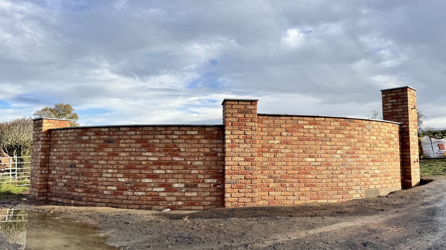 Completed curved brick wall with entrance piers and coping