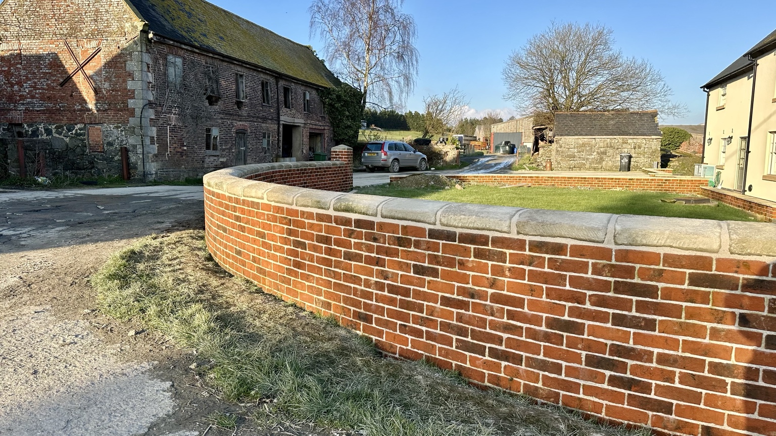 Completed curved brick garden wall with stone coping