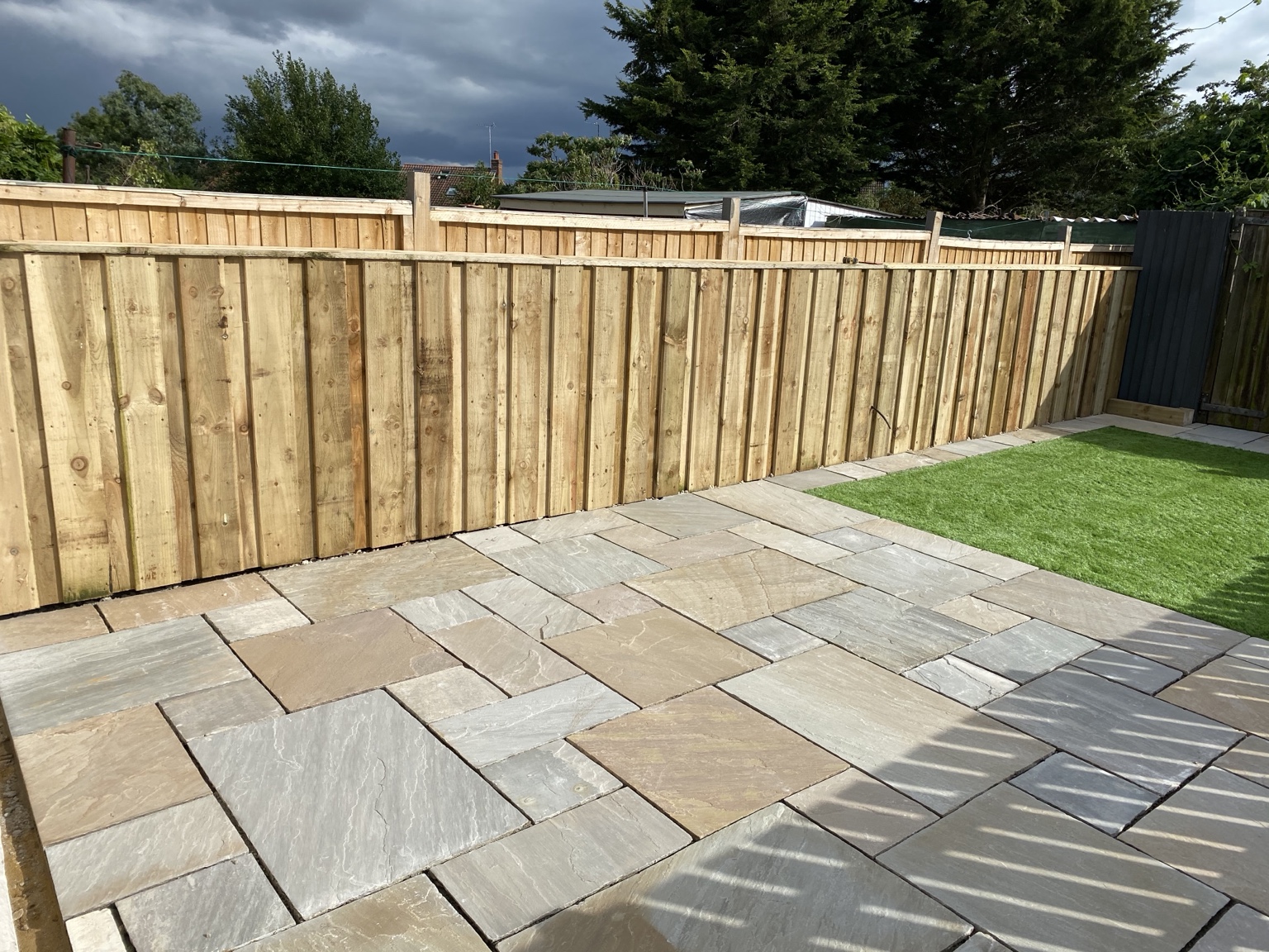 Indian sandstone patio laid around a garden lawn