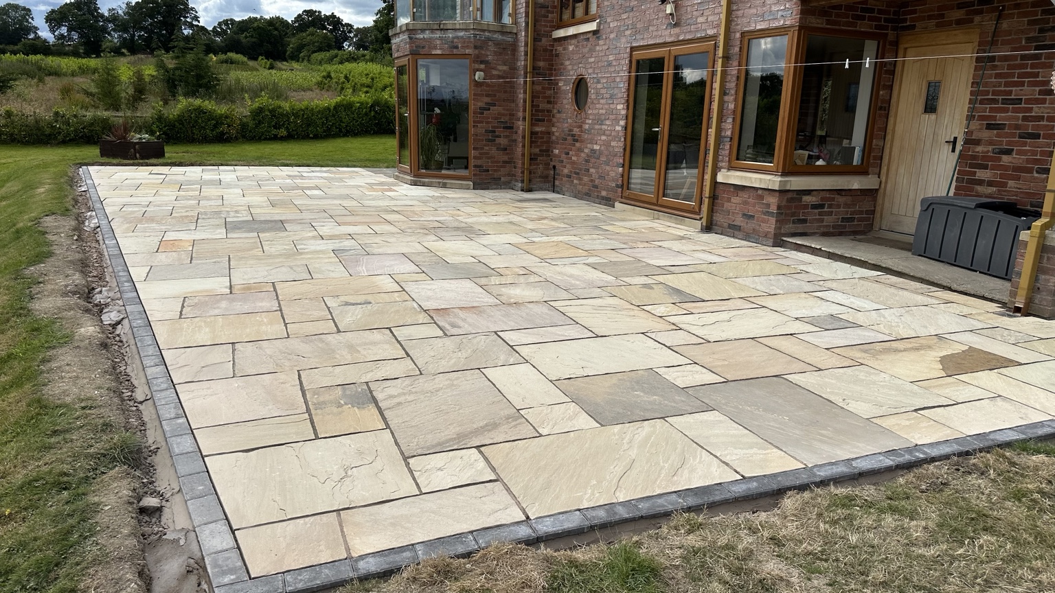 Finished Indian sandstone patio with brick edging